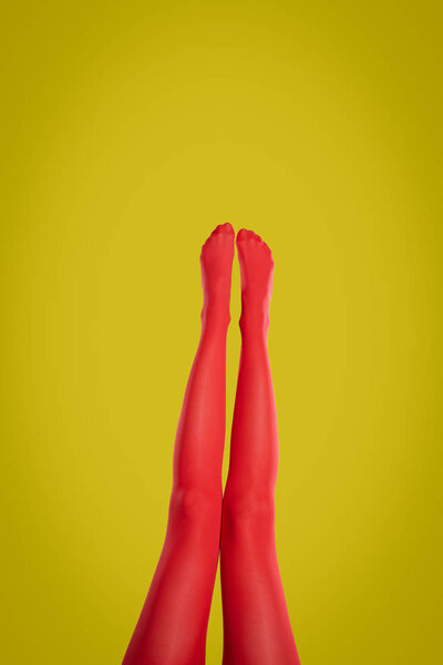Woman wearing red tights on yellow background, closeup of legs