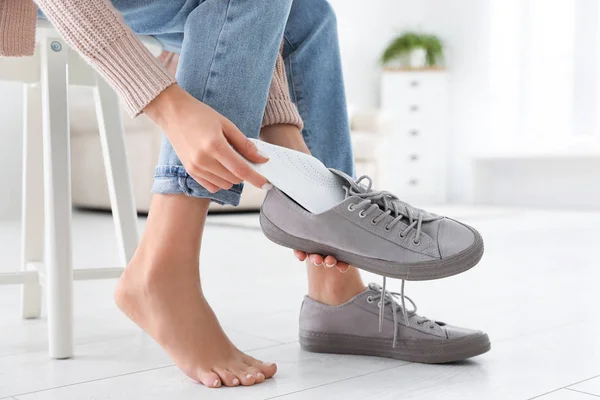 Woman putting orthopedic insole into shoe at home, closeup — Stock Photo, Image