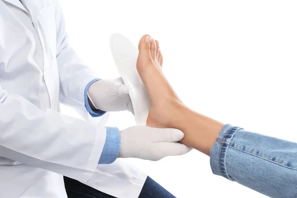 Male orthopedist fitting insole on patient's foot against white — Stock Photo, Image