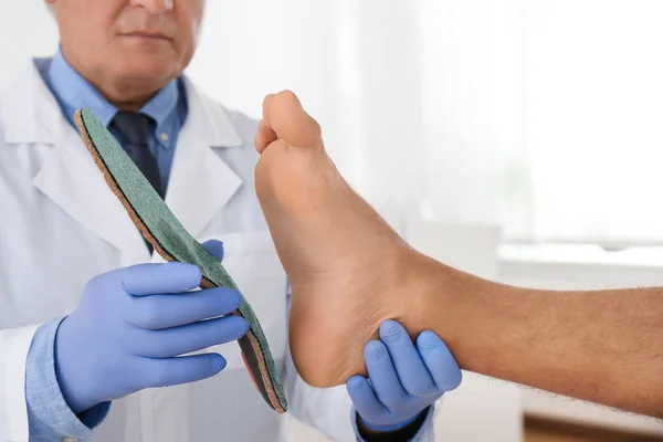 Male orthopedist fitting insole on patient's foot in clinic, clo — Stock Photo, Image