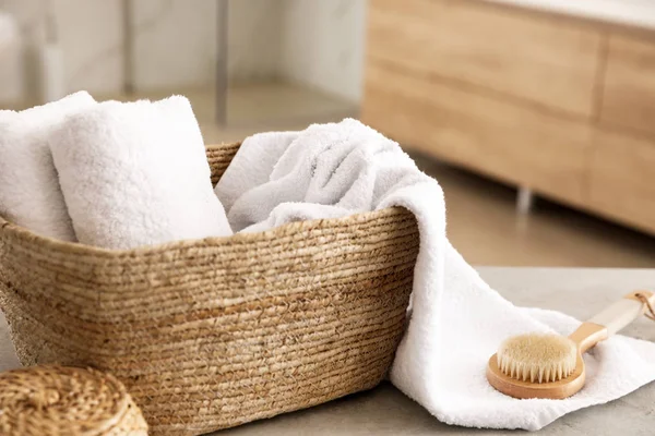 Proutěný koš s čistými ručníky a masážní kartáč na stole v ba — Stock fotografie