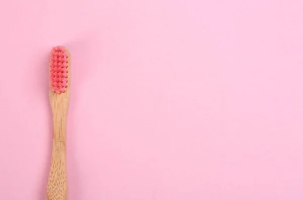 Szczoteczka do zębów wykonana z bambusa na różowym tle, widok z góry. Przestrzeń — Zdjęcie stockowe