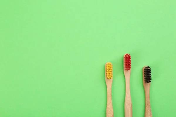 Escovas de dentes naturais feitas com bambu em fundo verde, plano — Fotografia de Stock