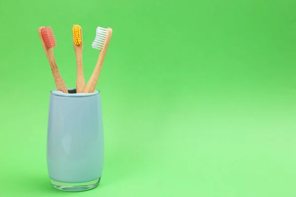 Bamboo toothbrushes in holder on green background, space for tex — Stock Photo, Image