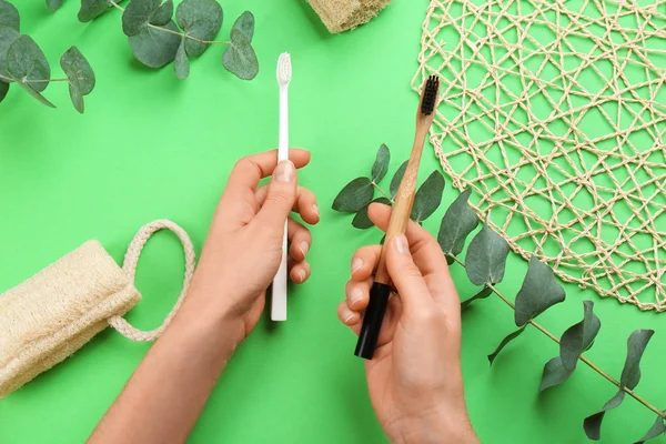 Woman holding natural bamboo and plastic toothbrushes over green — Stock Photo, Image