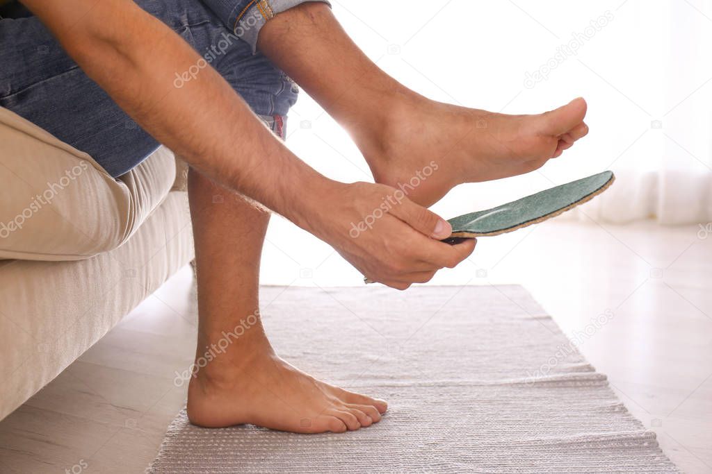 Man fitting orthopedic insole at home, closeup