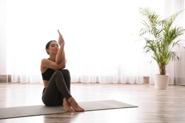 Genç bir kadın yoga stüdyosunda kartal asana alıştırması yapıyor. Garudasana Po