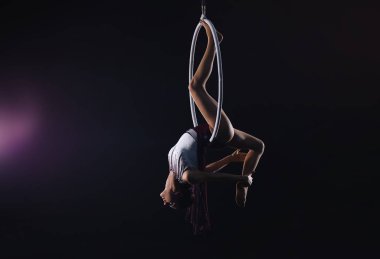 Genç bir kadın hava halkası üzerinde akrobatik bir element sergiliyor. 