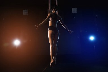 Genç bir kadın içerideki hava ipeklerinde akrobatik hareketler yapıyor.