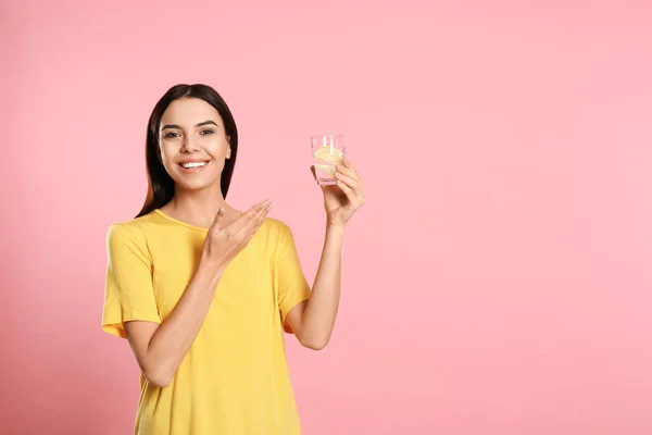 ピンクの背景においしいレモン水と美しい若い女性. — ストック写真