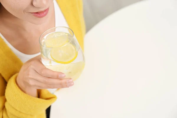 젊은 여자가 흰 탁자 위에서 레몬 물을 마시고 있습니다. ( ㄱ ) — 스톡 사진