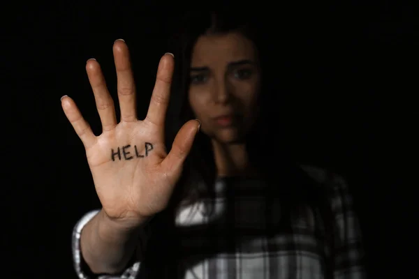 Abusado joven mujer mostrando palma con palabra AYUDA contra negro bac — Foto de Stock