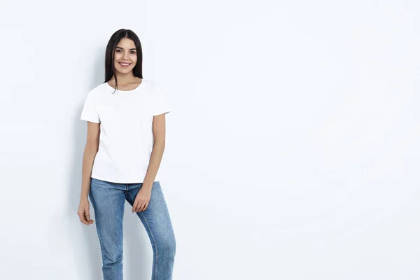 Wanita muda dengan celana jeans bergaya dengan latar belakang terang. Ruang untuk teks — Stok Foto