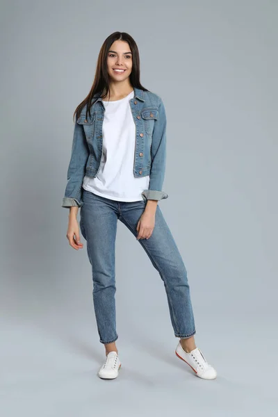 Mujer joven en jeans con estilo sobre fondo gris — Foto de Stock