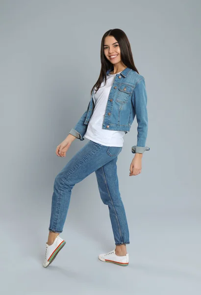 Jonge vrouw in stijlvolle jeans op grijze achtergrond — Stockfoto
