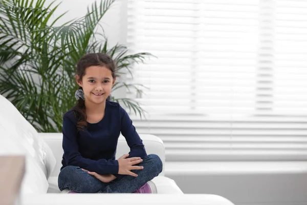 Menina bonito no sofá na sala de estar — Fotografia de Stock