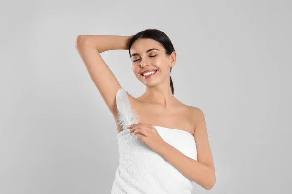 Young woman touching armpit with feather after epilation procedu — Stock Photo, Image