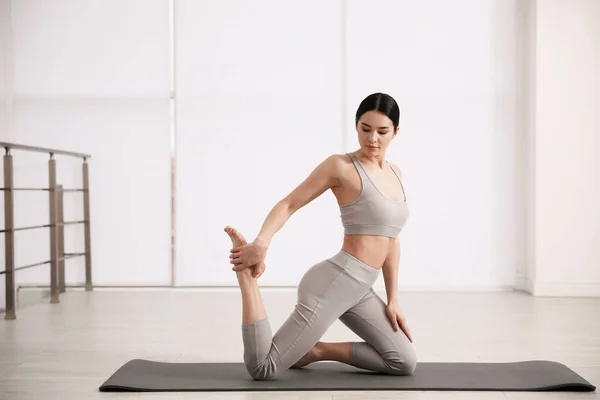 Mujer joven practicando One Legged King Pigeon asana en perno de yoga — Foto de Stock