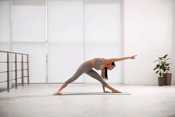 Giovane donna che pratica asana triangolo in studio di yoga. Utthita Tr — Foto Stock