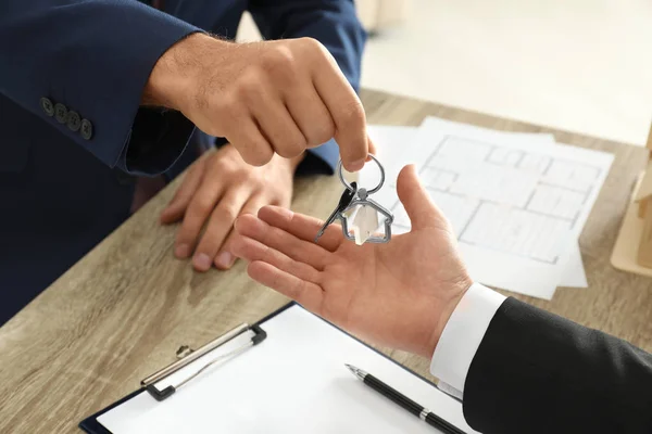 Agent immobilier donnant la clé au client à la table au bureau, fermer — Photo