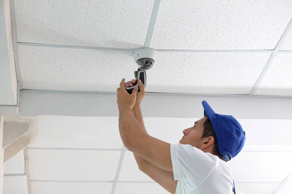 Técnico de instalação de câmera cctv no teto dentro de casa — Fotografia de Stock