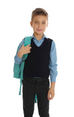 Beyaz arka planda sırt çantası olan okul üniformalı küçük bir çocuk.