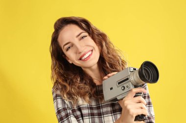 Sarı arka koltukta klasik video kamerası olan güzel genç bir kadın.