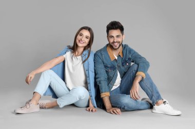 Gri arka planda oturan şık kotlu genç çift