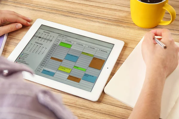 在办公室的平板电脑上使用日历应用程序的女性 — 图库照片
