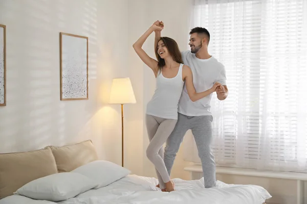 Adorável jovem casal dançando na cama em casa — Fotografia de Stock