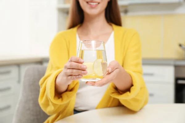 Mujer joven con vaso de agua de limón en la cocina, primer plano — Foto de Stock