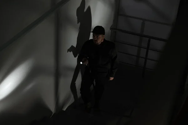 暗闇の中で階段を上る懐中電灯付き男性警備員 — ストック写真