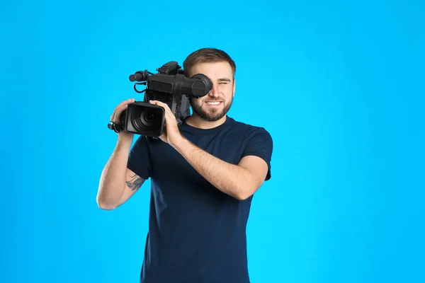Bediener mit professioneller Videokamera auf blauem Hintergrund — Stockfoto
