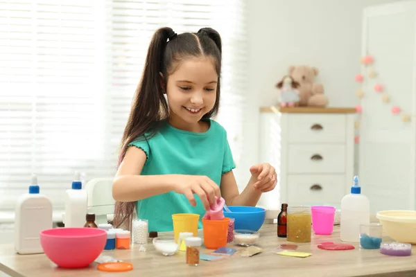 Menina bonito fazendo DIY lodo brinquedo na mesa dentro de casa — Fotografia de Stock