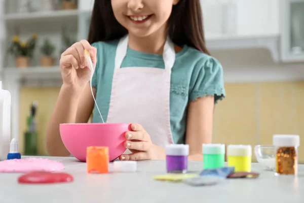 Маленькая девочка смешивает ингредиенты с силиконовой лопаткой за столом в — стоковое фото