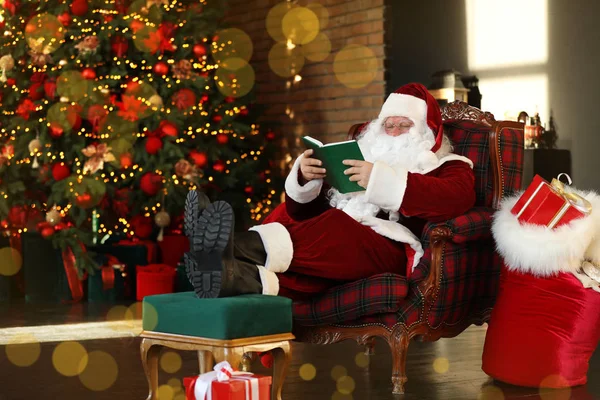 Santa Claus čtení knihy v blízkosti zdobené vánoční stromeček uvnitř — Stock fotografie