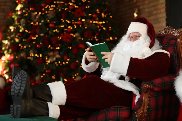 Άγιος Βασίλης ανάγνωση βιβλίο κοντά διακοσμημένα χριστουγεννιάτικο δέντρο σε εσωτερικούς χώρους — Φωτογραφία Αρχείου