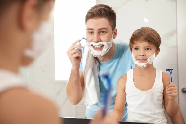 Dad shaving and son imitating him in bathroom