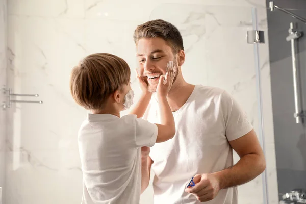 Dad and son with shaving foam on their faces having fun in bathr — ストック写真