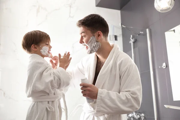 Vater sprüht Sohn im Badezimmer Rasierschaum ins Gesicht — Stockfoto