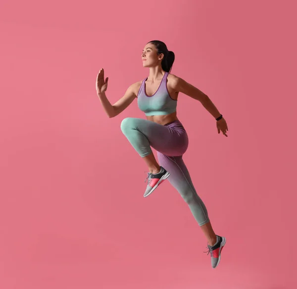 Mujer joven atlética corriendo sobre fondo rosa, vista lateral —  Fotos de Stock