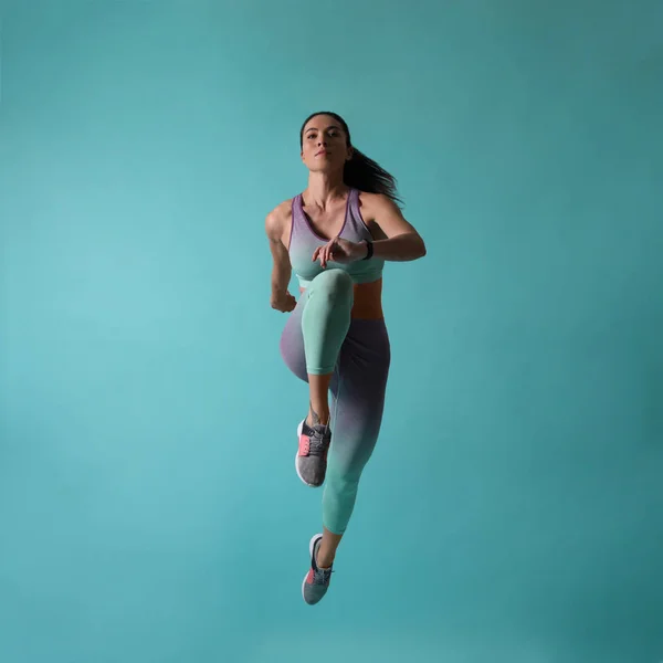 Atletica giovane donna in esecuzione su sfondo turchese — Foto Stock