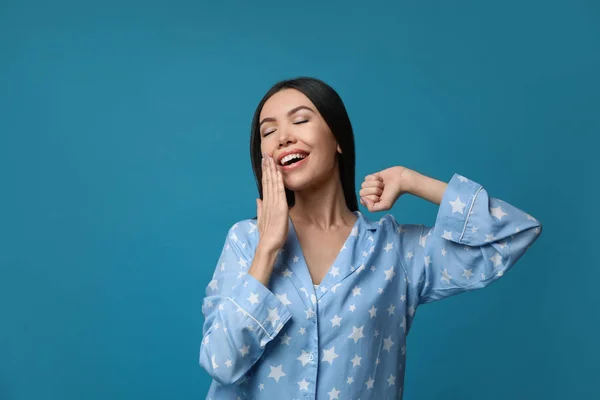 Hermosa mujer asiática en pijama bostezando sobre fondo azul. Cama —  Fotos de Stock