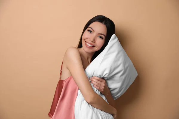 Vacker asiatisk kvinna med kudde på beige bakgrund. Sängdags — Stockfoto