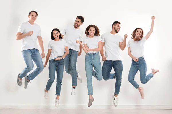 Grupo Jóvenes Jeans Elegantes Saltando Cerca Pared Blanca — Foto de Stock