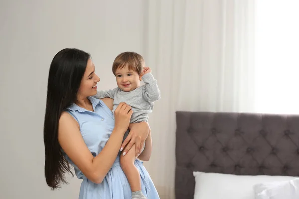 Niñera joven con lindo bebé en el dormitorio. Espacio para texto — Foto de Stock