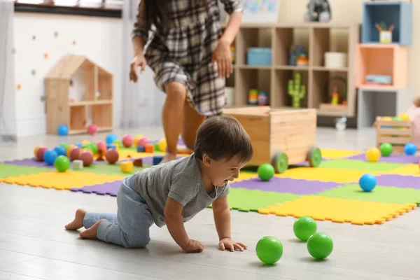 Маленькая няня и симпатичный малыш играют с игрушками дома — стоковое фото