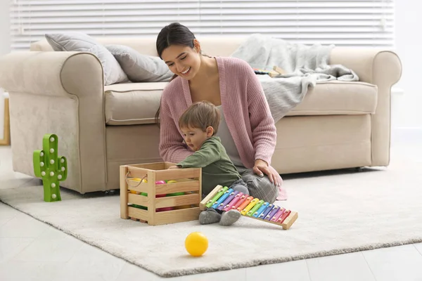 Niñera joven y lindo bebé jugando con juguetes en casa —  Fotos de Stock