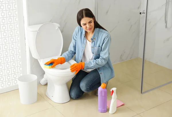 Young woman feeling disgust while cleaning