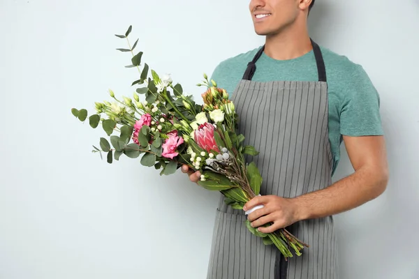 Florist with beautiful bouquet on light background, closeup